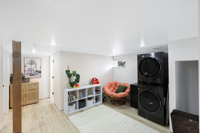 clothes washing area featuring light hardwood / wood-style flooring and stacked washer / dryer