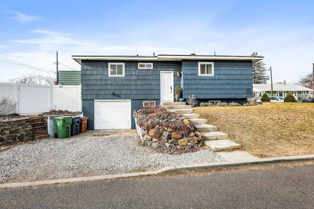 view of front of home with driveway, a garage, and fence