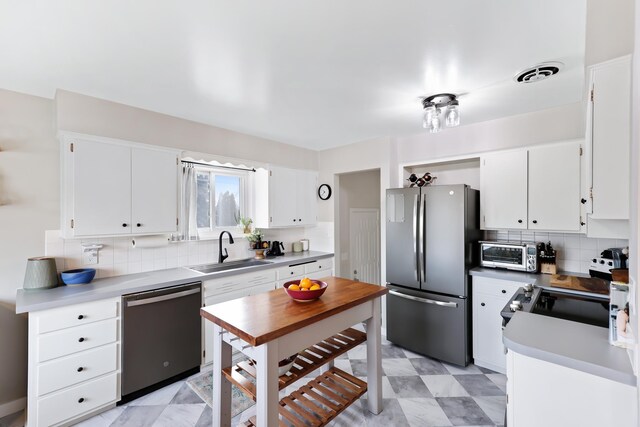 kitchen with stainless steel appliances, sink, decorative backsplash, and white cabinets