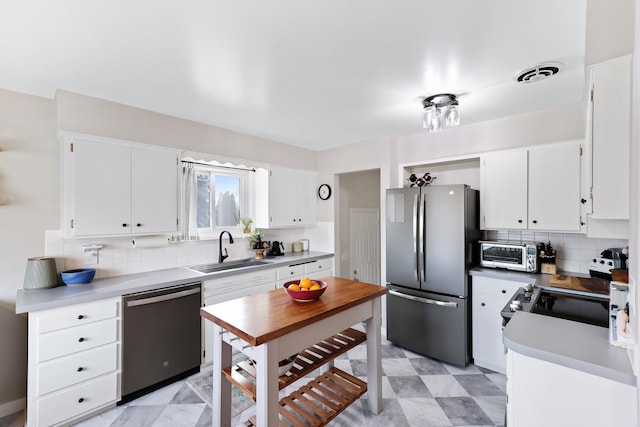 kitchen featuring white cabinetry, dishwashing machine, freestanding refrigerator, and a sink