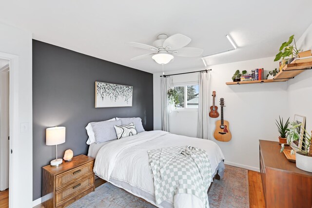 bedroom featuring a ceiling fan, baseboards, and wood finished floors