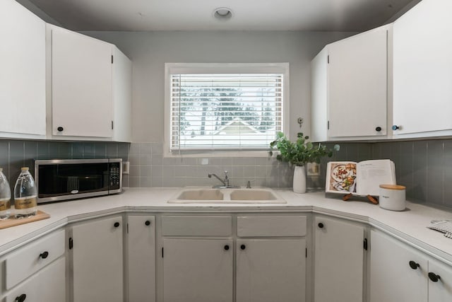 kitchen with tasteful backsplash, sink, and white cabinets