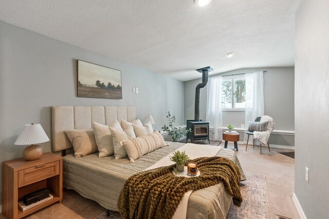 carpeted bedroom featuring vaulted ceiling, a textured ceiling, and a wood stove