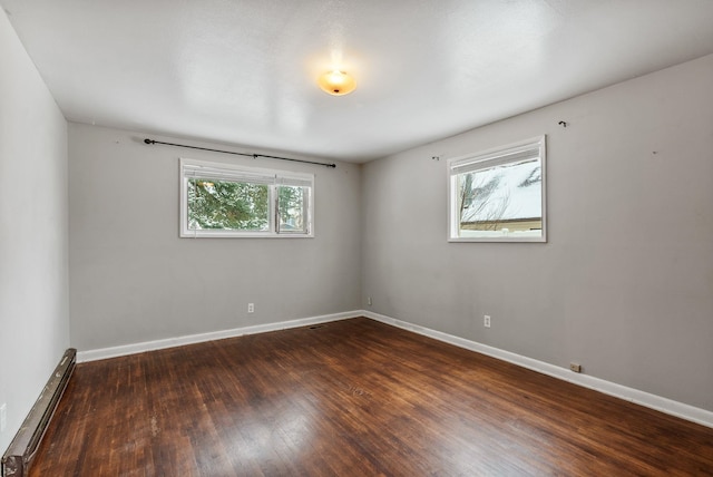 empty room featuring dark hardwood / wood-style flooring and a baseboard radiator