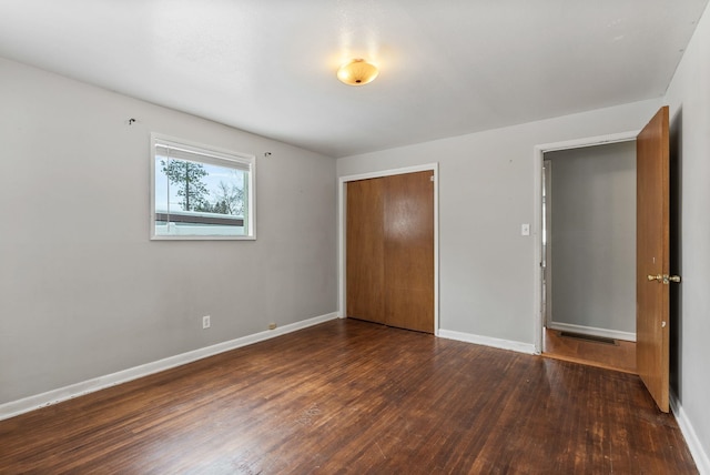 unfurnished bedroom with dark hardwood / wood-style floors and a closet