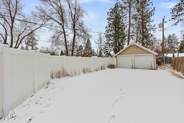 yard layered in snow featuring a garage and an outdoor structure