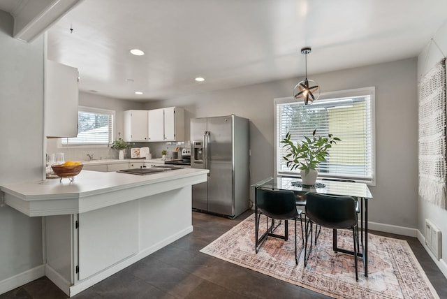 kitchen with white cabinetry, stainless steel fridge, decorative backsplash, hanging light fixtures, and kitchen peninsula