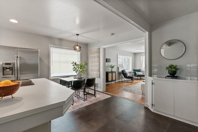 kitchen featuring stainless steel refrigerator with ice dispenser, pendant lighting, and backsplash