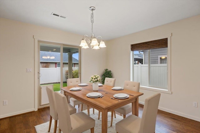 dining room with plenty of natural light, dark wood-type flooring, and a chandelier