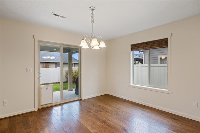 empty room featuring an inviting chandelier and hardwood / wood-style floors