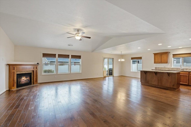 unfurnished living room featuring lofted ceiling, sink, dark hardwood / wood-style floors, a textured ceiling, and ceiling fan with notable chandelier