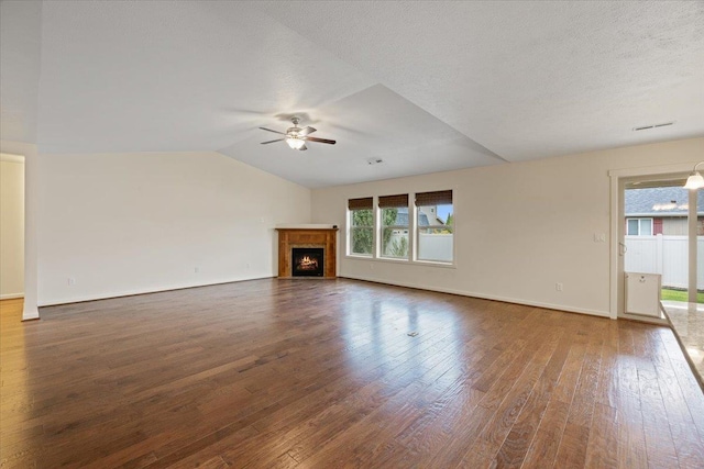 unfurnished living room with ceiling fan, lofted ceiling, dark hardwood / wood-style floors, and a textured ceiling