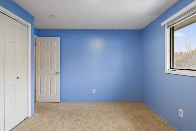 unfurnished bedroom with light colored carpet, a closet, and a textured ceiling