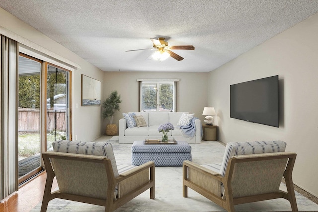 living room featuring ceiling fan and a textured ceiling