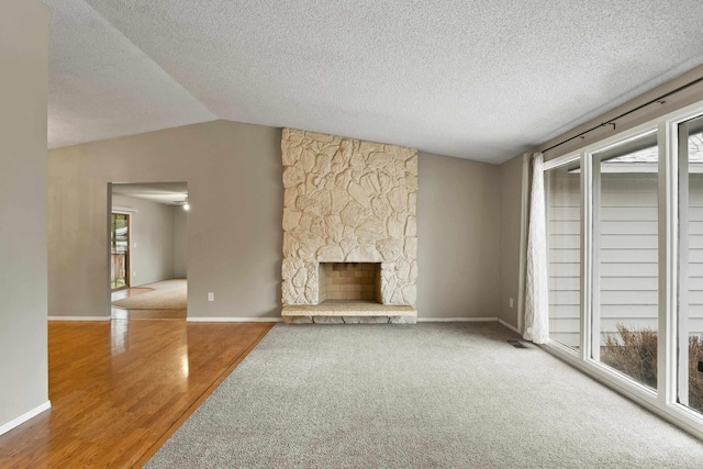 unfurnished living room featuring lofted ceiling, a fireplace, wood-type flooring, and a textured ceiling