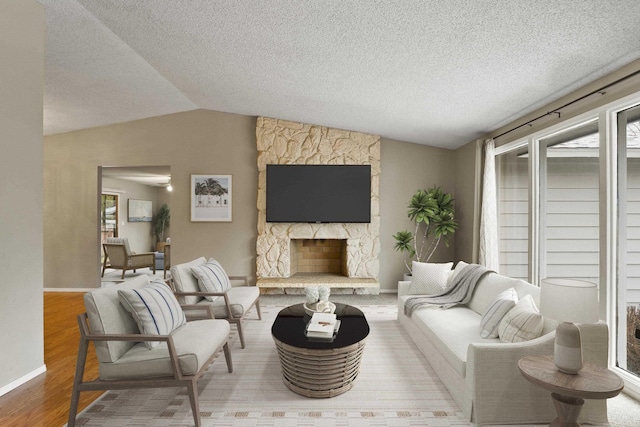 living room with lofted ceiling, a stone fireplace, hardwood / wood-style floors, and plenty of natural light