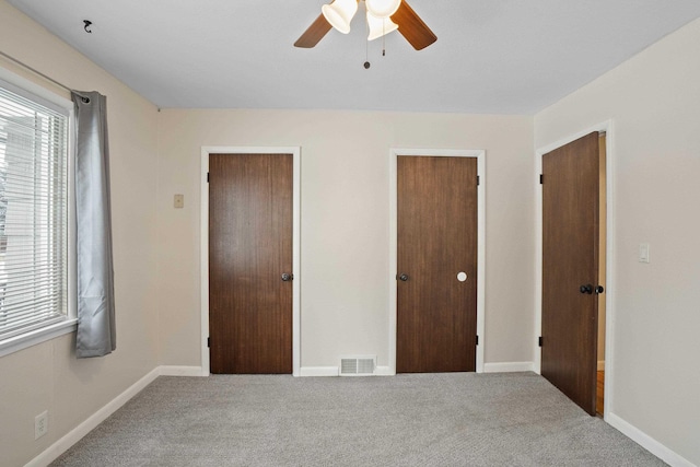 unfurnished bedroom with multiple closets, ceiling fan, and carpet