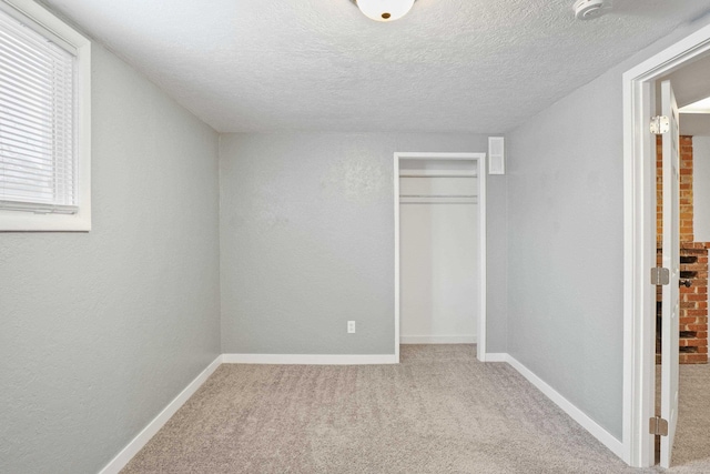 unfurnished bedroom featuring light carpet, a closet, and a textured ceiling