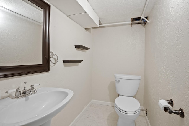 bathroom with sink, a textured ceiling, and toilet