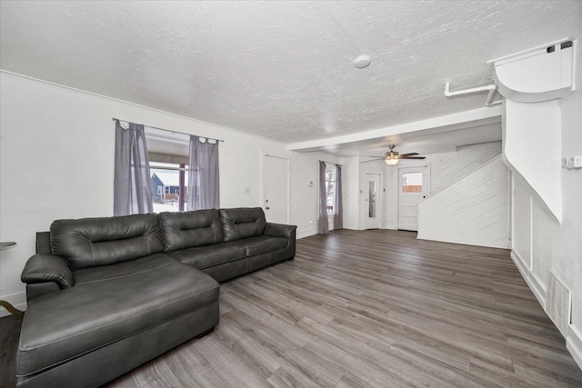 living room with ceiling fan, a textured ceiling, wood-type flooring, and a healthy amount of sunlight