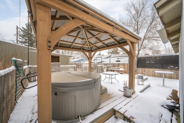 snow covered deck with a gazebo and a hot tub