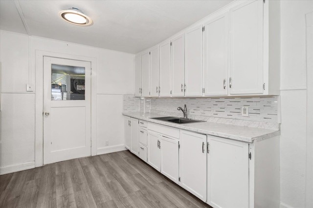 kitchen featuring tasteful backsplash, sink, white cabinets, and light wood-type flooring