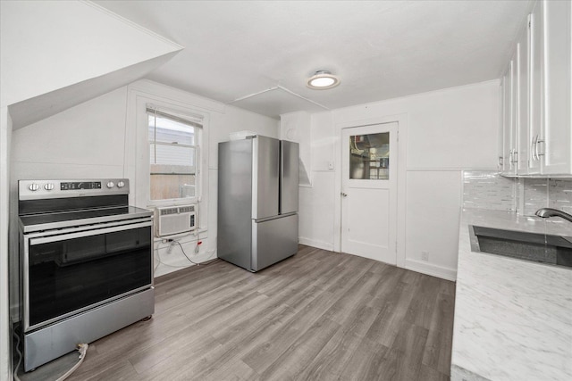 kitchen with appliances with stainless steel finishes, white cabinetry, lofted ceiling, sink, and light wood-type flooring