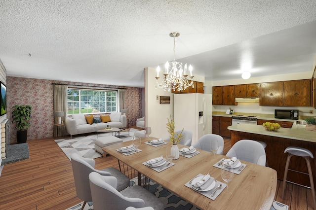 dining room featuring an inviting chandelier, hardwood / wood-style floors, and a textured ceiling