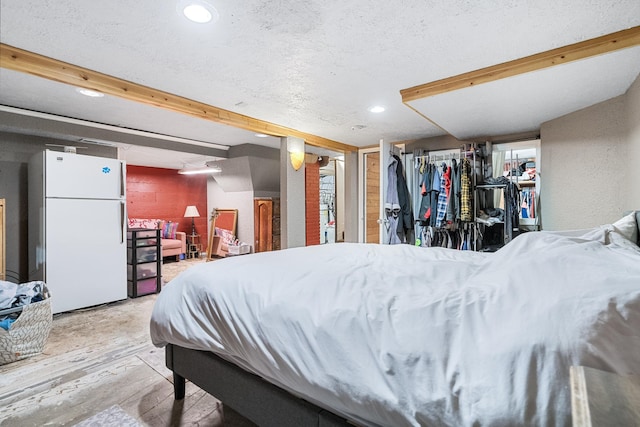 bedroom with white refrigerator, light hardwood / wood-style floors, a textured ceiling, and beamed ceiling