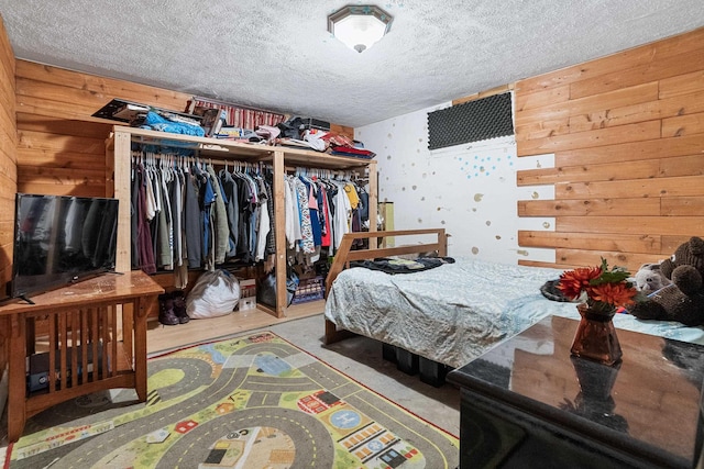 bedroom featuring a closet, a textured ceiling, and wood walls