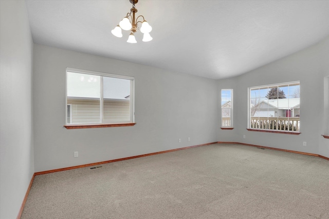 carpeted spare room with lofted ceiling and a chandelier