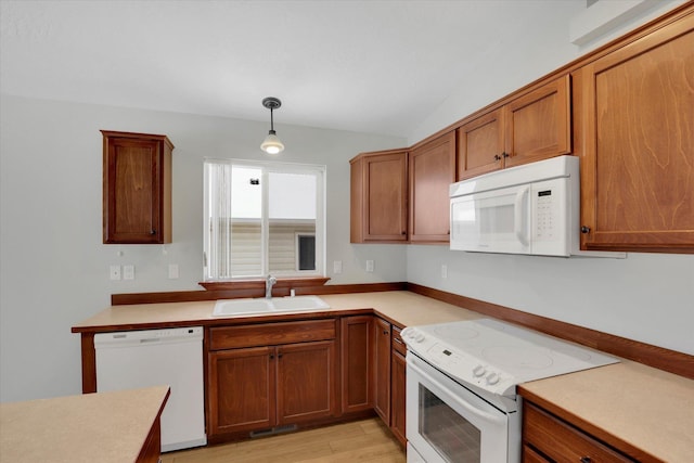 kitchen with vaulted ceiling, sink, hanging light fixtures, white appliances, and light hardwood / wood-style flooring