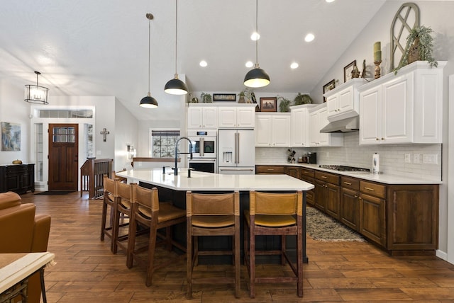 kitchen with white appliances, light countertops, dark wood finished floors, and under cabinet range hood