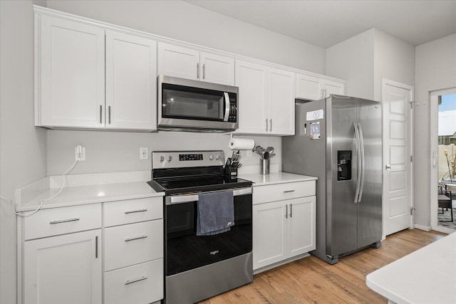 kitchen featuring stainless steel appliances, light countertops, light wood-style flooring, and white cabinets