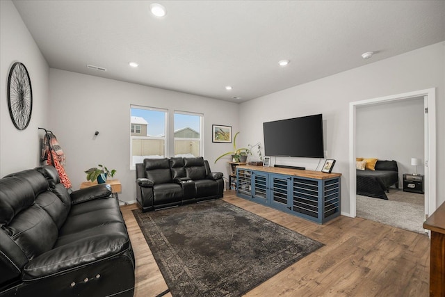 living room with recessed lighting, visible vents, and wood finished floors