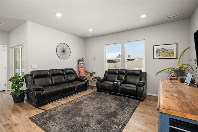 living room featuring light wood-style flooring, visible vents, baseboards, and recessed lighting