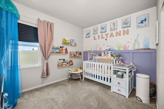 bedroom with a nursery area, carpet floors, wainscoting, and baseboards