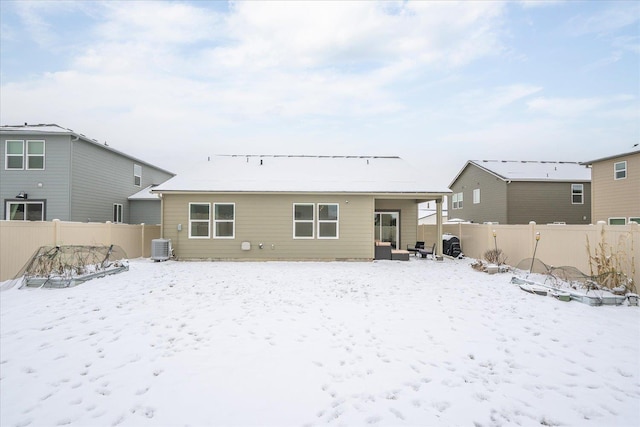 snow covered rear of property with a fenced backyard and central air condition unit