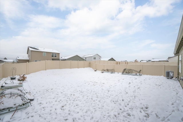 yard covered in snow featuring central AC unit and a fenced backyard