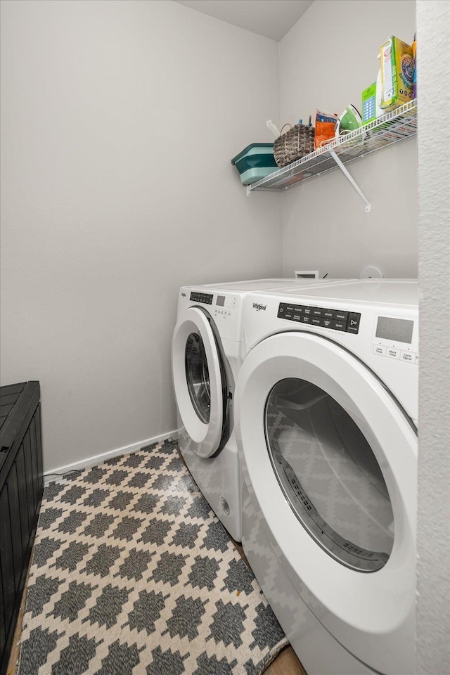 washroom featuring washing machine and dryer, laundry area, and baseboards