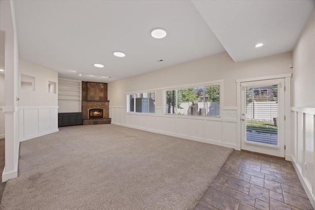 unfurnished living room with a large fireplace, carpet, and built in features