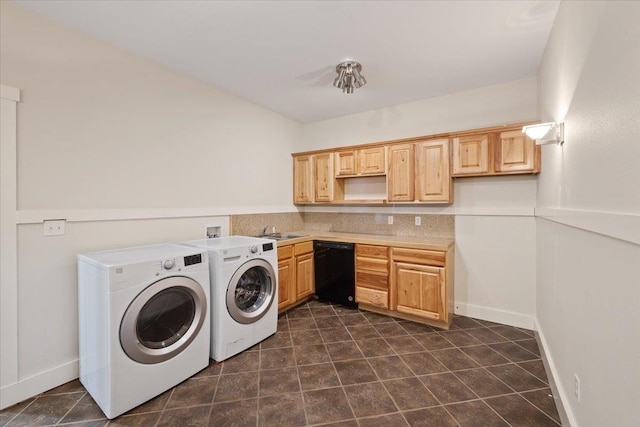 clothes washing area featuring washing machine and dryer, sink, and dark tile patterned flooring