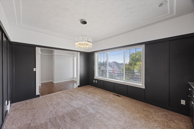 unfurnished bedroom featuring carpet flooring, a raised ceiling, and a notable chandelier