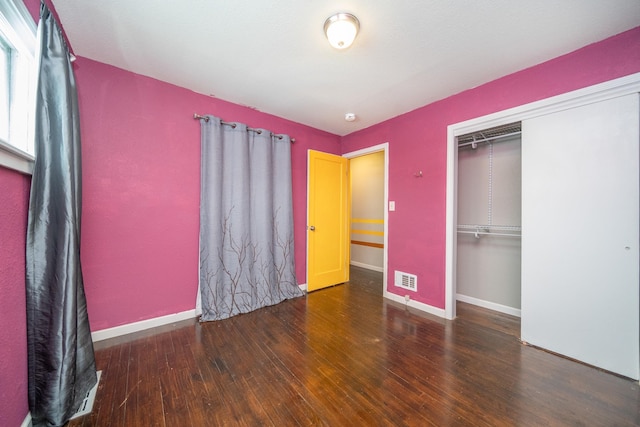 unfurnished bedroom with dark hardwood / wood-style floors and a closet