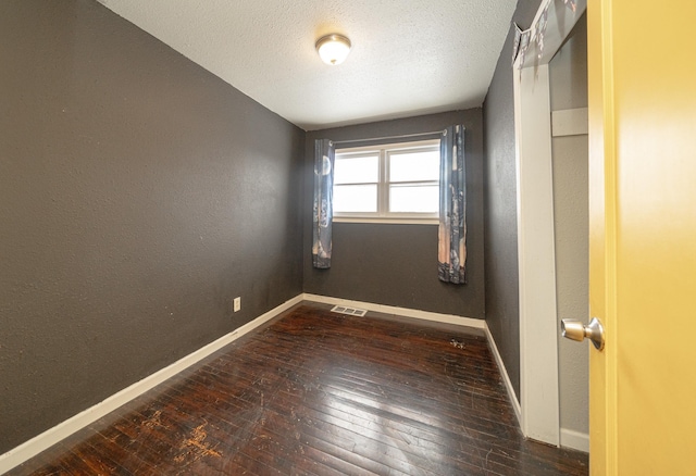 spare room featuring dark hardwood / wood-style floors and a textured ceiling