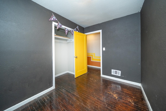 unfurnished bedroom with dark hardwood / wood-style floors and a closet