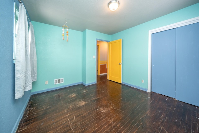 unfurnished bedroom featuring a closet and dark hardwood / wood-style floors