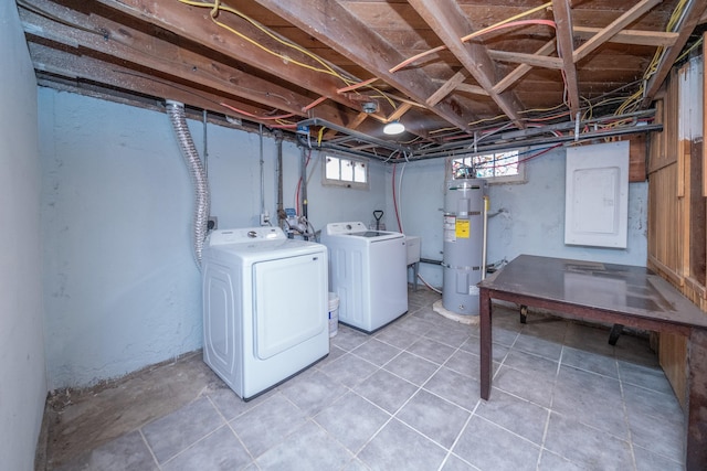 basement with electric panel, washer and clothes dryer, and strapped water heater