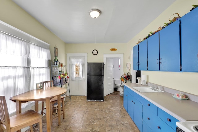 kitchen featuring black refrigerator, sink, range, and blue cabinetry