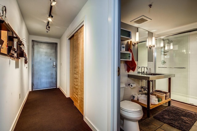 hallway featuring tile walls, sink, track lighting, and dark tile patterned floors